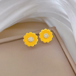 Detailed macro shot of yellow sunflower earrings with sparkling zircon core on beige tray