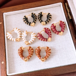 Detail of heart-shaped woven earrings in four colors arranged in a wooden jewelry box