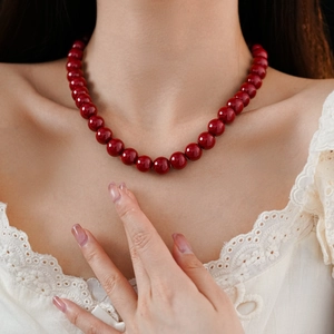 Close-up of elegant red round bead necklace worn by a model in white lace top