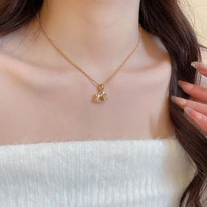 Close-up of a gold-plated rocking horse pendant necklace with sparkling zircons on a model