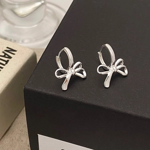 Gros plan de boucles d'oreilles nœuds en argent poli sur une boîte cadeau noire