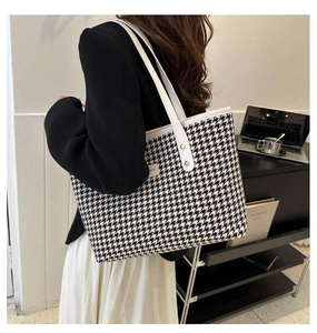 Classic houndstooth tote bag shown on model highlighting its large size and shoulder fit