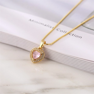 Detail view of heart necklace with pink gemstone and zircon halo on marble surface