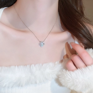 Close-up of a silver four-leaf clover pendant necklace with sparkling zircon on a woman's neck