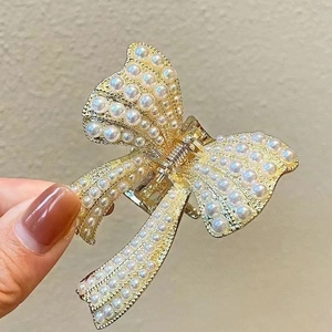 Detail of golden metal butterfly hair claw clip with cream pearls and spring mechanism