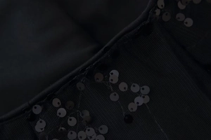 Detalle macro de lentejuelas negras cosidas sobre malla para falda de cintura alta