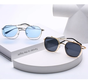 Close-up of retro metal flip-up sunglasses with silver and gold frames on white props