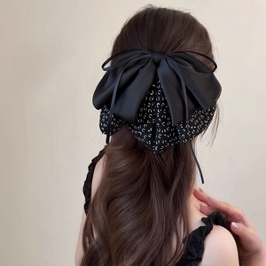 Detailed back view of a layered black satin and floral bow hair clip on a model