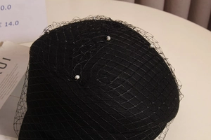 Detailed macro view of black mesh netting with pearl accents on wool beret cap