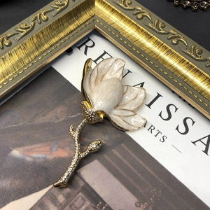 Detail of elegant white enamel magnolia brooch with gold plating on an art book background