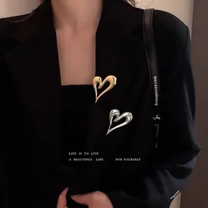Minimalist fluid heart brooch set in gold and silver on a black suit lapel