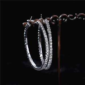 Sparkling oversized silver hoop earrings with dense crystal rhinestones on a display stand