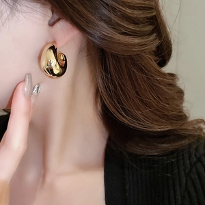 Gros plan de boucles d'oreilles créoles dorées en forme de goutte montrant un fini poli
