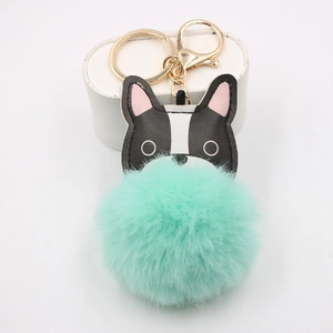 Close-up of mint green faux fur pompom keychain with a black and white bulldog leather charm