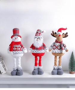 Three plush Christmas dolls featuring Santa, snowman and reindeer on white mantelpiece