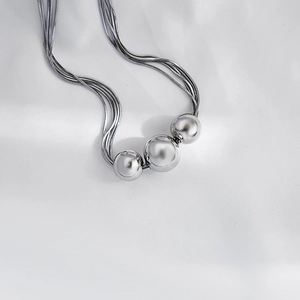 Close-up of polished silver spheres and multi-layer snake chains on white silk fabric