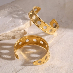 Detail of gold wide cuff bracelet with hollow round holes and twisted rope edges