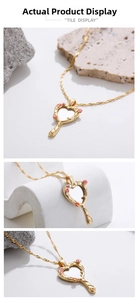 Detail of golden heart mirror pendant necklace with enamel flowers on stone background