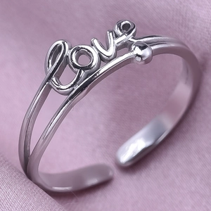 Close-up of silver stainless steel Love ring on pink silk fabric background