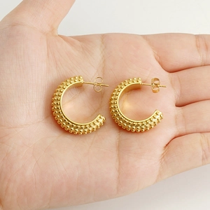 Golden geometric hoop earrings with textured beads shown on palm for size reference