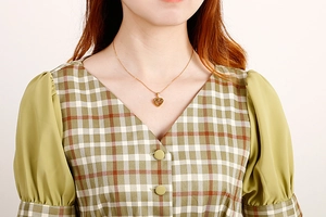 Close-up of a gold heart-shaped pendant necklace worn on a woman's neck for gift ideas