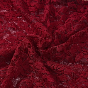 Vue macro d'un tissu en dentelle rouge foncé aux motifs floraux et textures ajourées