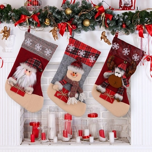 Three Christmas stockings with Santa, Snowman, and Reindeer hung on a festive fireplace