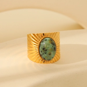 Detail of vintage gold-plated titanium ring with green turquoise stone and radial texture