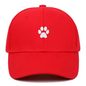 Close-up of red cotton baseball cap featuring white embroidered animal paw print detail