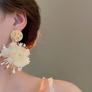 Detail of elegant gold hammered stud with cream translucent chiffon flower earring
