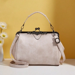 Detail of cream vintage frame bag with leaf texture, lace trim, and dark metal handle