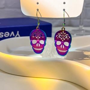 Macro shot of skull earrings with iridescent gradient plating on white jewelry stand