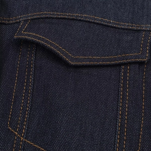 Vista macro del tessuto denim twill blu scuro con cuciture a contrasto arancioni sulla tasca