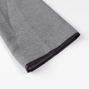 Detailed close-up of grey wool fabric with elegant black leather piping and stitching