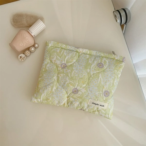 Macro detail of quilted floral makeup bag with light green and pink flower patterns