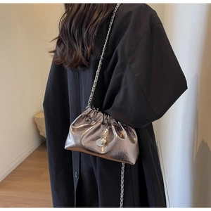 Close-up of silver pleated cloud bag with metal chain strap and decorative pearl pendant