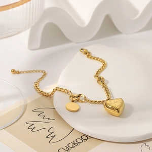 Vintage Gliederkette Armband mit Herzanhänger und runder Plakette auf weißem gewelltem Hintergrund