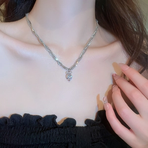 Close-up of a silver heart-shaped pendant necklace with cubic zirconia on a model's neck