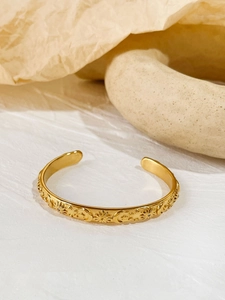 Detailed view of gold plated open bangle with sun moon and star embossed patterns