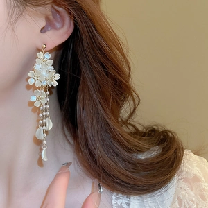 Elegant floral tassel earrings with imitation pearls and crystals on a female model