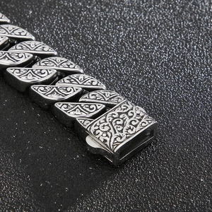Macro shot of vintage engraved floral patterns on a silver-toned men's titanium steel bracelet