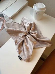 Close-up of champagne gold satin scrunchie with a Hand Made label and silk texture
