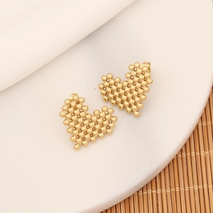 Macro shot of gold mosaic heart stud earrings crafted with polished metallic spheres