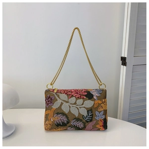 Detailed view of brown sequin evening clutch with floral embroidery and golden chain strap