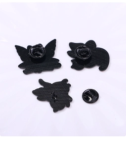 Détail du dos en métal peint noir et des fermoirs papillon des broches en forme de chat