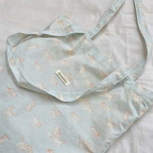 Close-up of cute orange cat print on light blue canvas tote bag with woven brand label