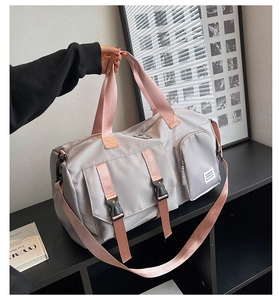 Detail of grey travel duffel bag with pink straps and secure buckle closures