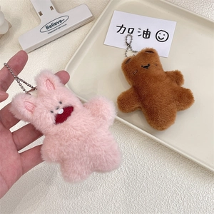 Detail of plush pink rabbit and brown bear keychains with metal chains on a white tray