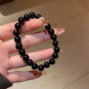 Close-up of polished black obsidian beaded bracelet with a translucent charm detail