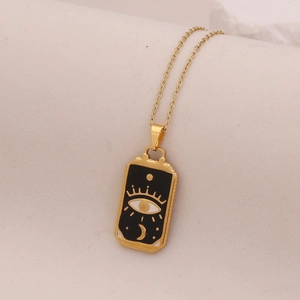 Macro view of gold celestial pendant with black enamel evil eye and crescent moon details